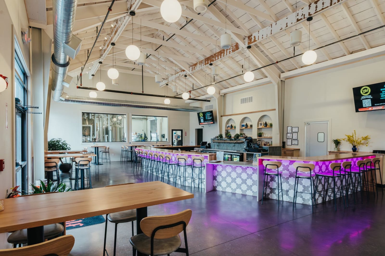 The DeWolf taproom with a long wooden table in the foreground and the tiled bar, lit purple, behind it